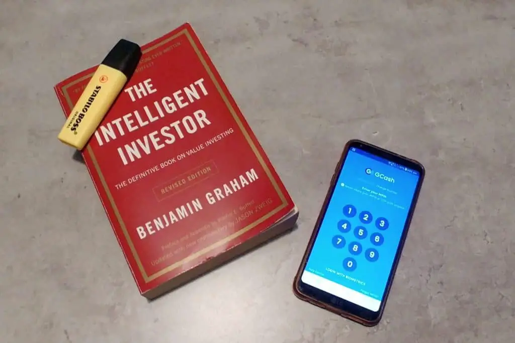 Intelligent Investor book with market and cell phone with GCash app.