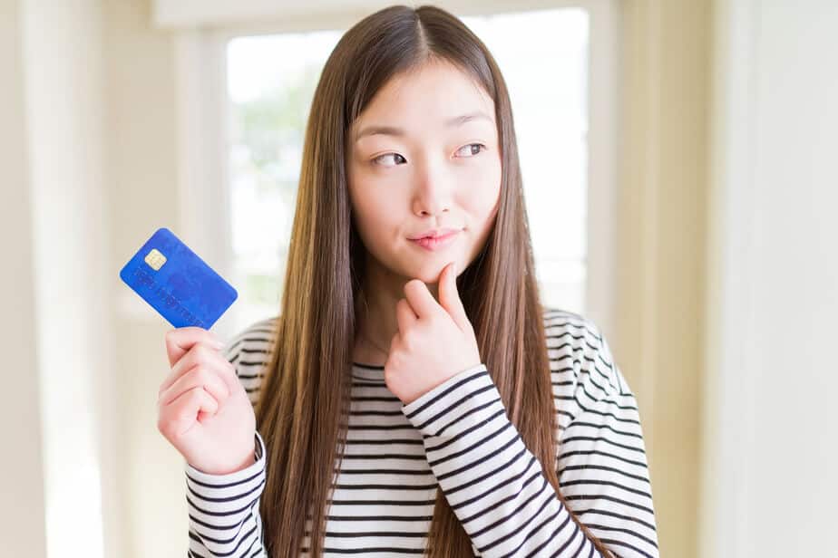 Girl thinking while holding a blue plastic card.