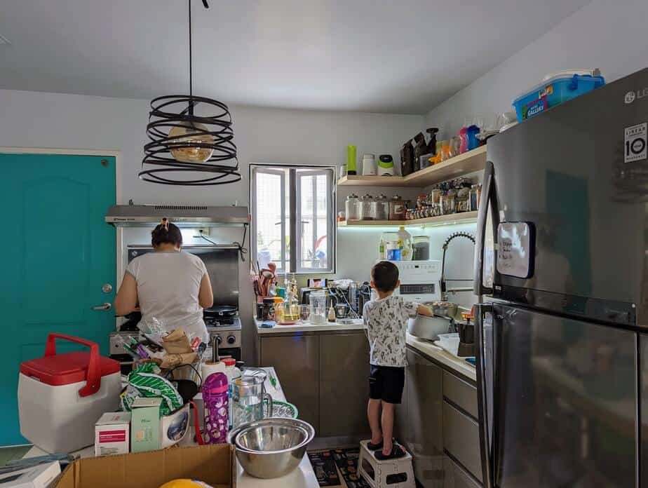 Mother and son cooking in messy kitchen.