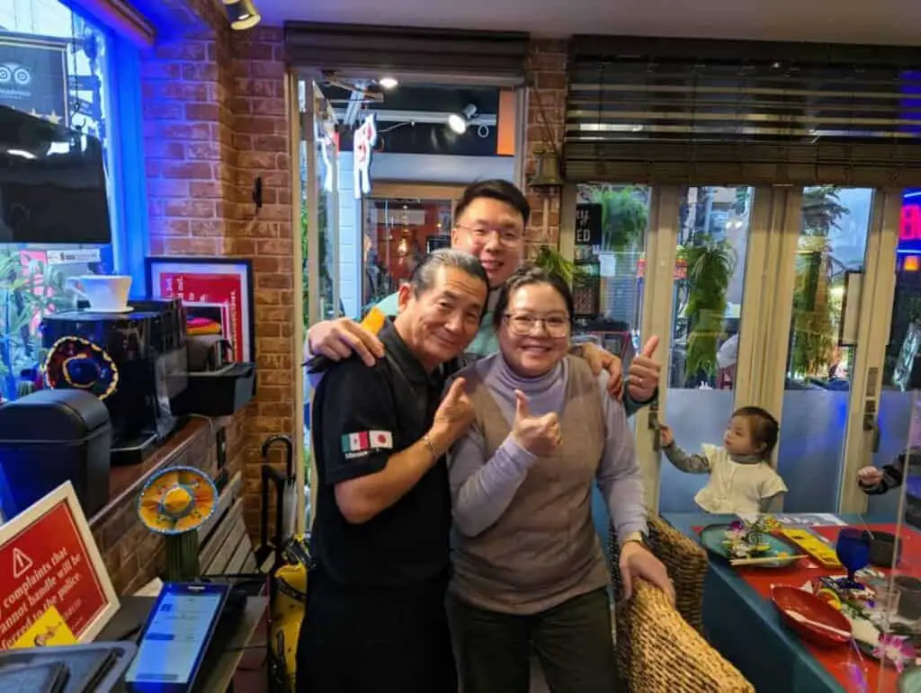 A couple taking a picture with a Japanese chef.